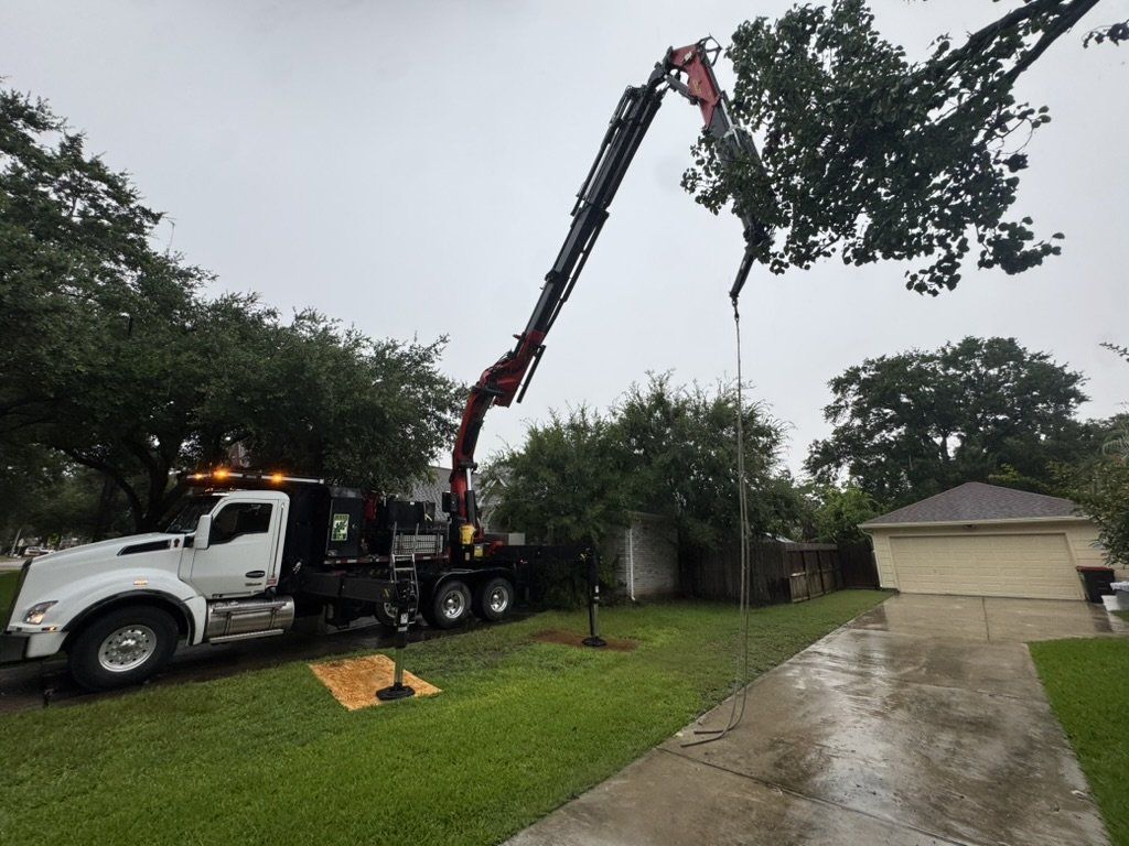 Grapple saw truck working over a residential property in the rain